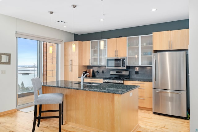 kitchen featuring sink, hanging light fixtures, backsplash, dark stone counters, and appliances with stainless steel finishes