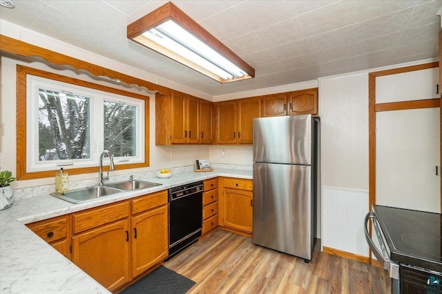 kitchen with sink, black dishwasher, light hardwood / wood-style floors, range, and stainless steel refrigerator