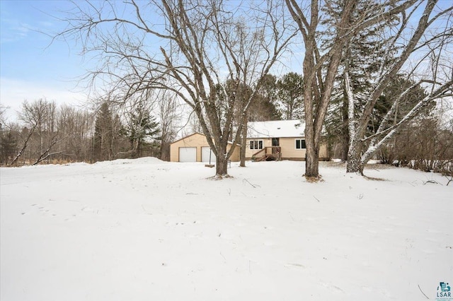 yard layered in snow featuring an outdoor structure and a garage