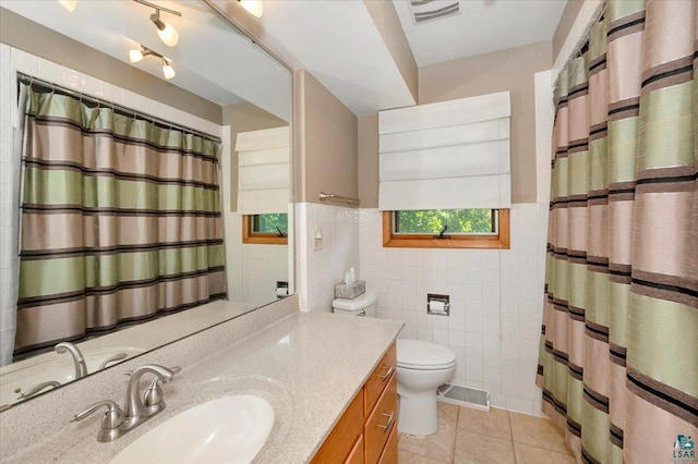 bathroom featuring tile patterned flooring, vanity, toilet, and tile walls