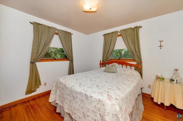 bedroom with multiple windows and hardwood / wood-style floors