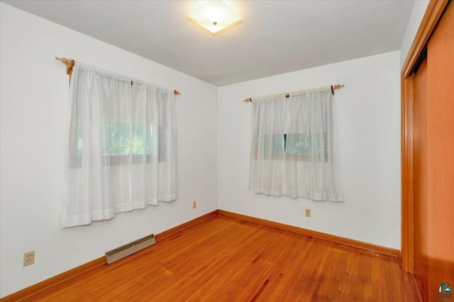 unfurnished room featuring a baseboard radiator and hardwood / wood-style flooring