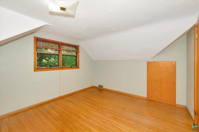 additional living space featuring lofted ceiling and light hardwood / wood-style flooring