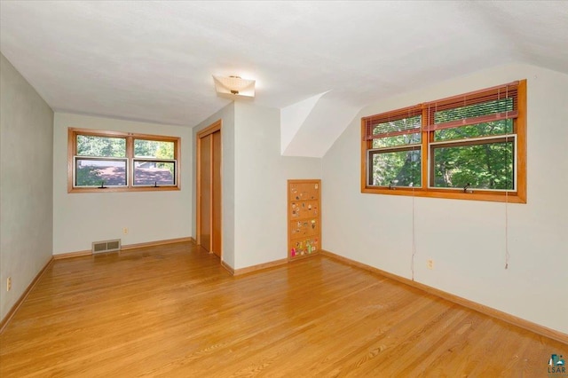 additional living space with light hardwood / wood-style flooring and lofted ceiling