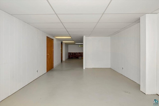 basement featuring a paneled ceiling and wooden walls