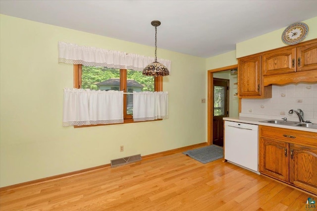 kitchen with tasteful backsplash, sink, pendant lighting, light hardwood / wood-style flooring, and dishwasher