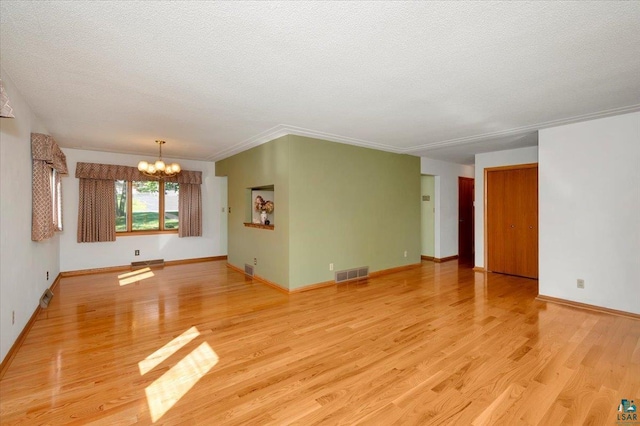 empty room featuring a textured ceiling, light hardwood / wood-style flooring, and a chandelier