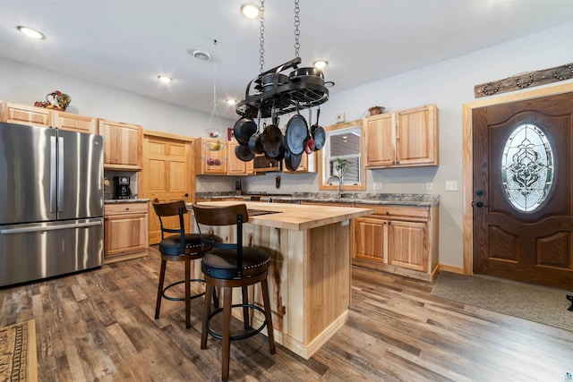 kitchen with stainless steel fridge, dark hardwood / wood-style flooring, a kitchen island, and wooden counters