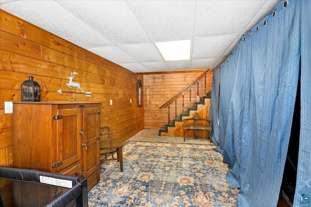 interior space with a paneled ceiling and wooden walls