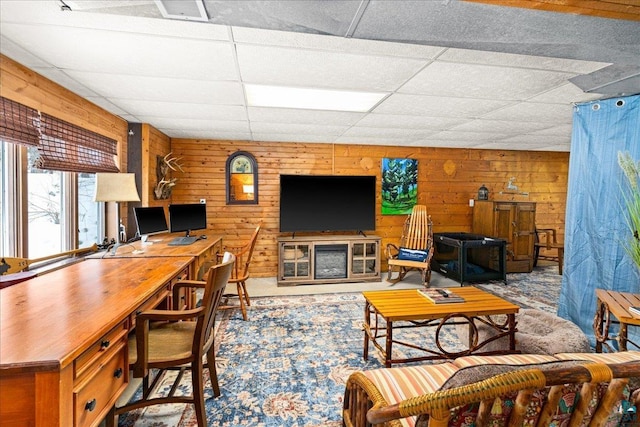 living room featuring a paneled ceiling and wooden walls