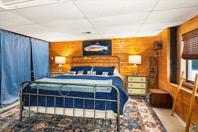 bedroom with wooden walls and a drop ceiling