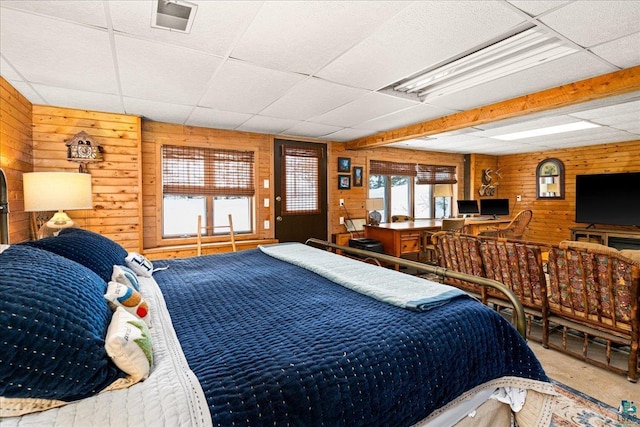 bedroom featuring wood walls, carpet flooring, and a drop ceiling