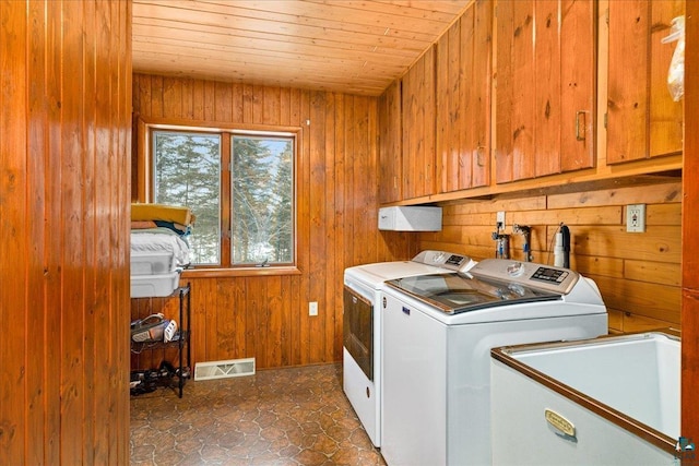 laundry area featuring separate washer and dryer, cabinets, wooden ceiling, and wood walls