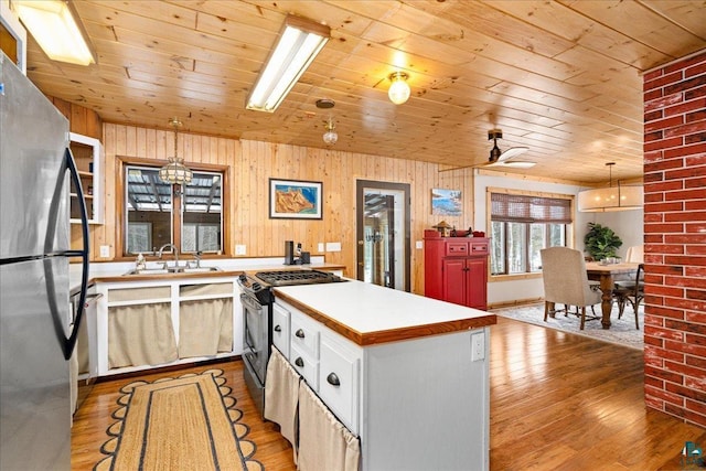 kitchen featuring stainless steel appliances, wooden ceiling, sink, and hanging light fixtures