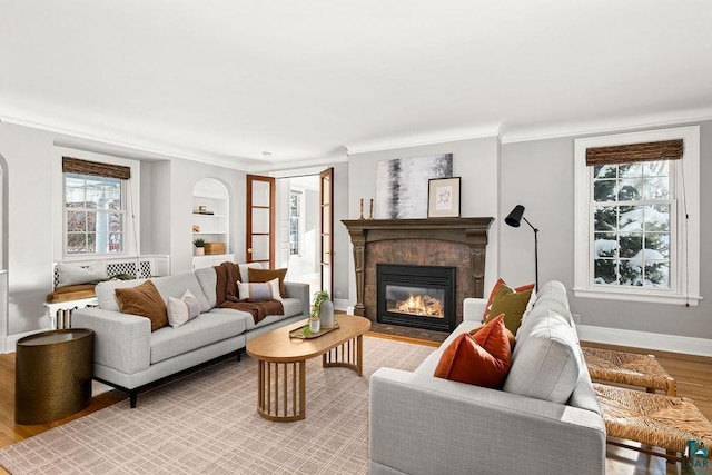 living room featuring ornamental molding, built in shelves, and light hardwood / wood-style flooring