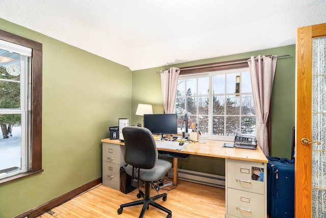 home office with light hardwood / wood-style flooring and a baseboard radiator