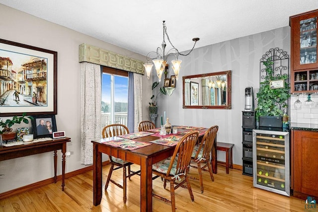 dining space with an inviting chandelier, light hardwood / wood-style floors, and wine cooler