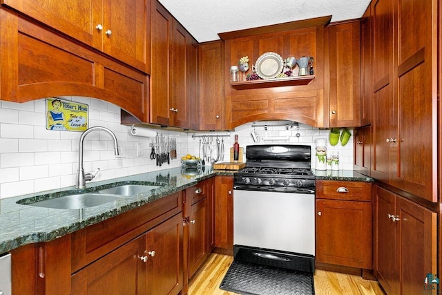 kitchen featuring sink, decorative backsplash, range with gas stovetop, and light hardwood / wood-style floors