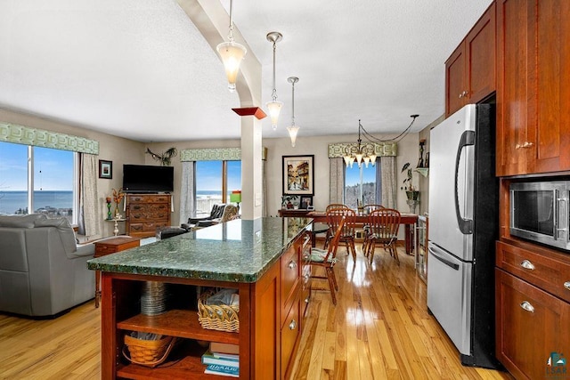 kitchen featuring pendant lighting, appliances with stainless steel finishes, a kitchen island, an inviting chandelier, and light wood-type flooring