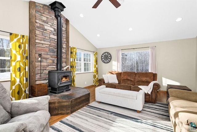 living room with vaulted ceiling, ceiling fan, a wood stove, and hardwood / wood-style floors