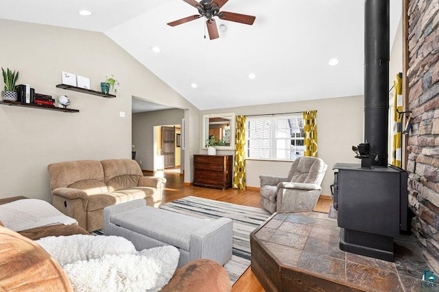 living room featuring hardwood / wood-style flooring, a wood stove, ceiling fan, and vaulted ceiling