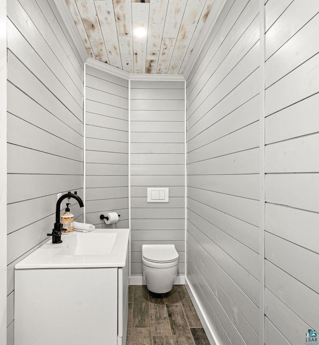 bathroom with wooden ceiling, toilet, vanity, and wooden walls