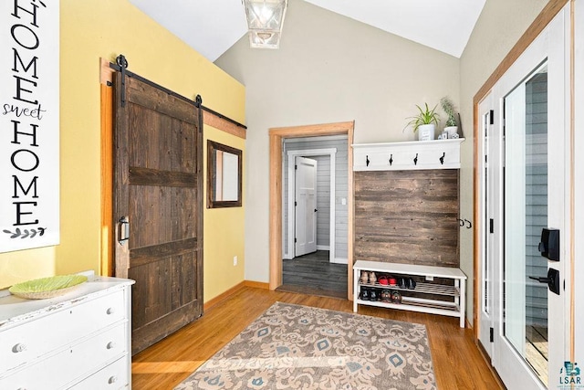 mudroom with vaulted ceiling, a barn door, and light wood-type flooring