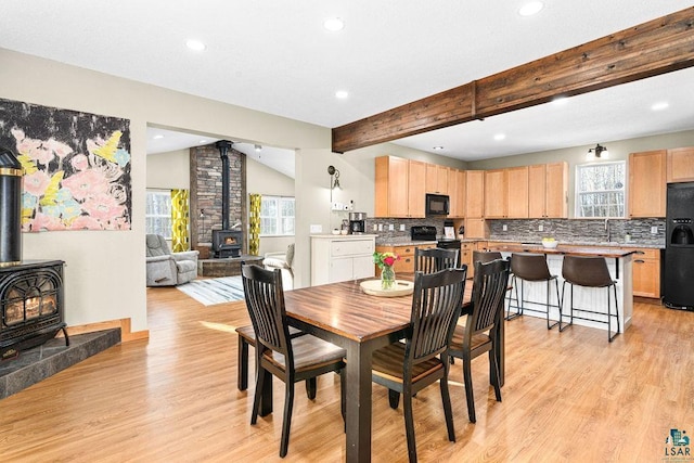 dining space featuring a healthy amount of sunlight, a wood stove, and light hardwood / wood-style flooring