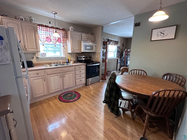 kitchen featuring hanging light fixtures, sink, white appliances, and a textured ceiling