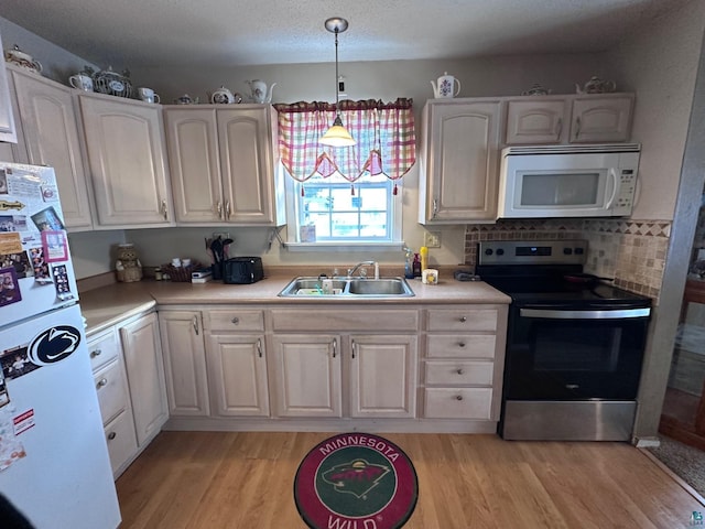 kitchen featuring sink, pendant lighting, white cabinets, and white appliances