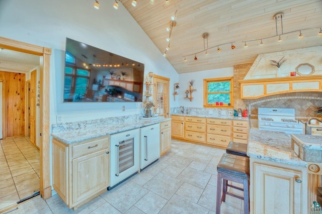 kitchen with light stone countertops, beverage cooler, wood walls, and pendant lighting