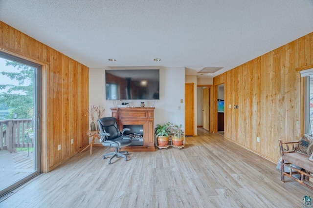 living room featuring wooden walls, a textured ceiling, and light hardwood / wood-style floors