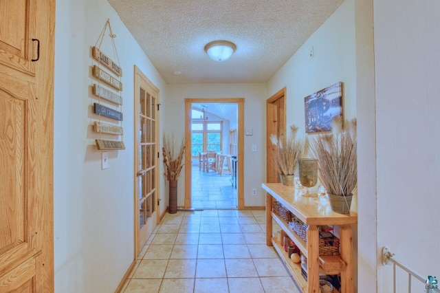 hall featuring a textured ceiling, light tile patterned floors, and french doors