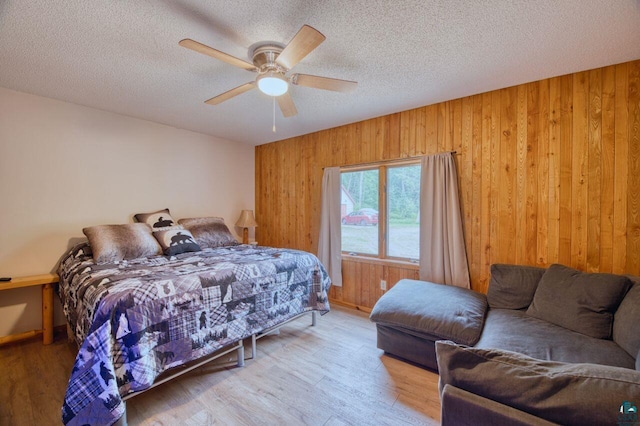 bedroom with a textured ceiling, ceiling fan, and wood walls