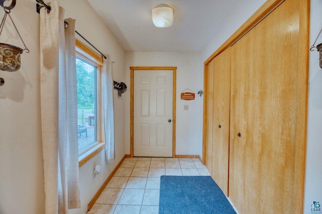 entryway with a textured ceiling and light tile patterned flooring