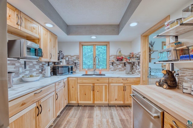 kitchen featuring decorative backsplash, sink, light wood-type flooring, appliances with stainless steel finishes, and light brown cabinets