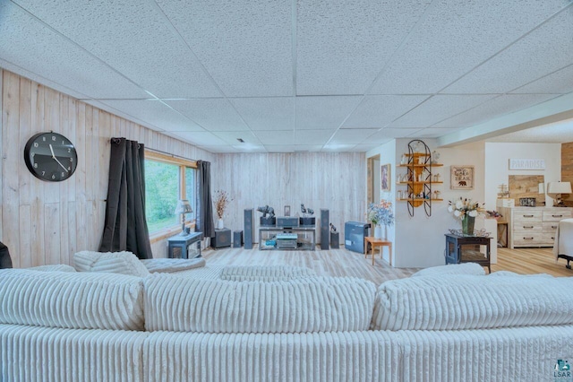 living room with a drop ceiling and wood walls