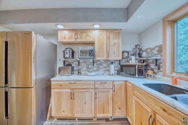 kitchen with decorative backsplash, appliances with stainless steel finishes, sink, and light brown cabinetry