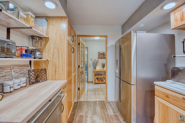 kitchen with decorative backsplash, light brown cabinets, appliances with stainless steel finishes, and wood counters