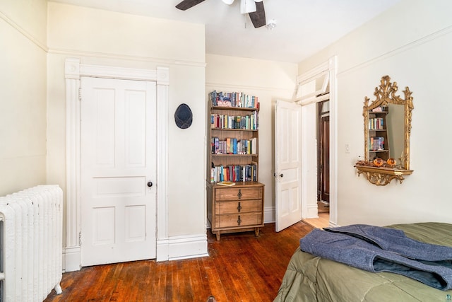 bedroom featuring ceiling fan, dark wood-type flooring, radiator, and a closet