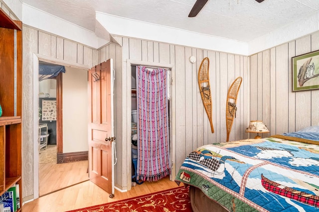 bedroom with ceiling fan, hardwood / wood-style floors, and wooden walls