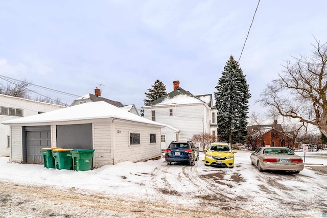 view of snowy exterior with an outbuilding and a garage