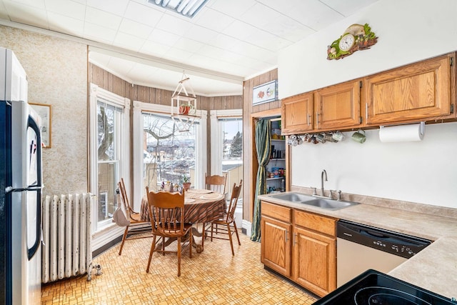 kitchen with dishwasher, wood walls, fridge, sink, and radiator