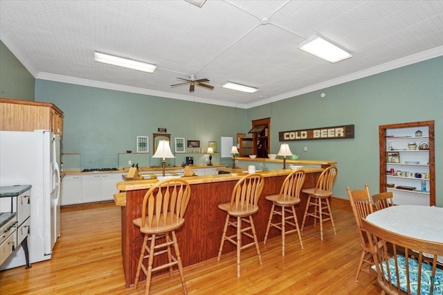 7596 Werner Rd, Virginia, MN 55720 - kitchen with white fridge with ice dispenser, crown molding, light hardwood / wood-style floors, and a breakfast bar