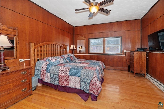 7596 Werner Rd, Virginia, MN 55720 - bedroom featuring a baseboard radiator, wood walls, light hardwood / wood-style flooring, and ceiling fan