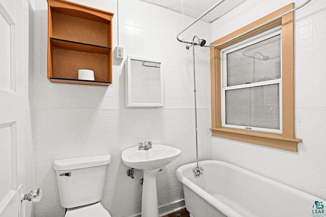 bathroom with a tub to relax in and toilet