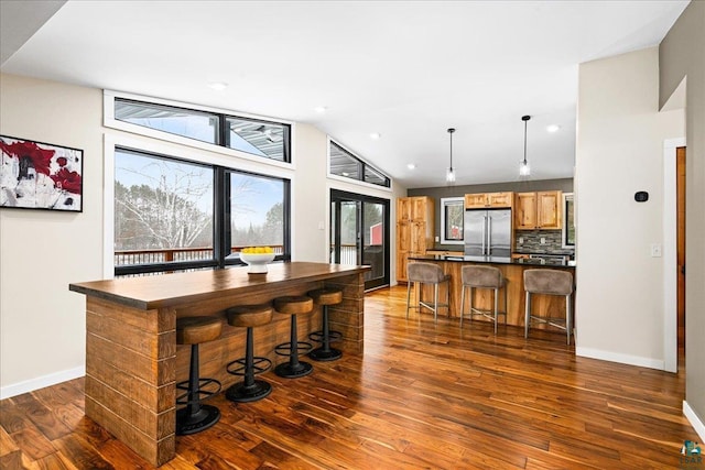 kitchen with a kitchen breakfast bar, backsplash, a center island, and stainless steel refrigerator