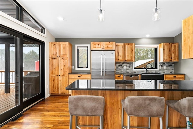 kitchen with tasteful backsplash, a kitchen breakfast bar, sink, decorative light fixtures, and stainless steel appliances