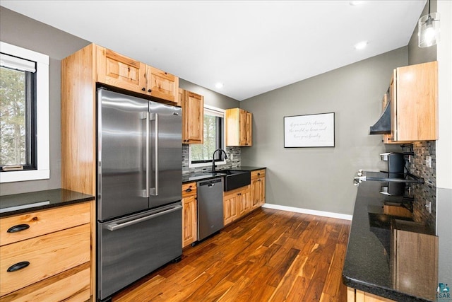 kitchen with appliances with stainless steel finishes, wall chimney exhaust hood, tasteful backsplash, sink, and dark hardwood / wood-style floors