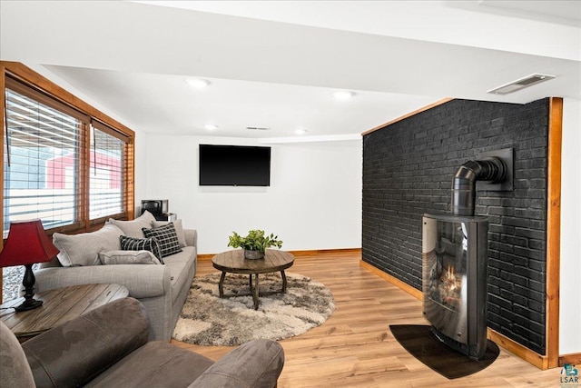 living room with light hardwood / wood-style floors and a wood stove